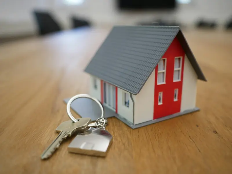 A house key on a ring beside a small model house
